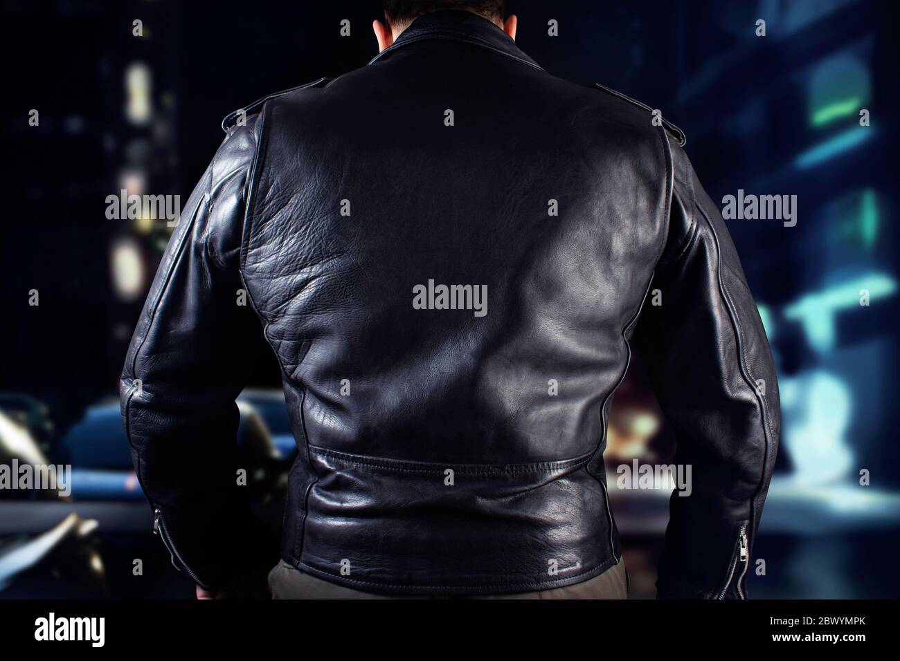 Closeup photo of a man in black leather biker jacket standing on black background. Stock Photo