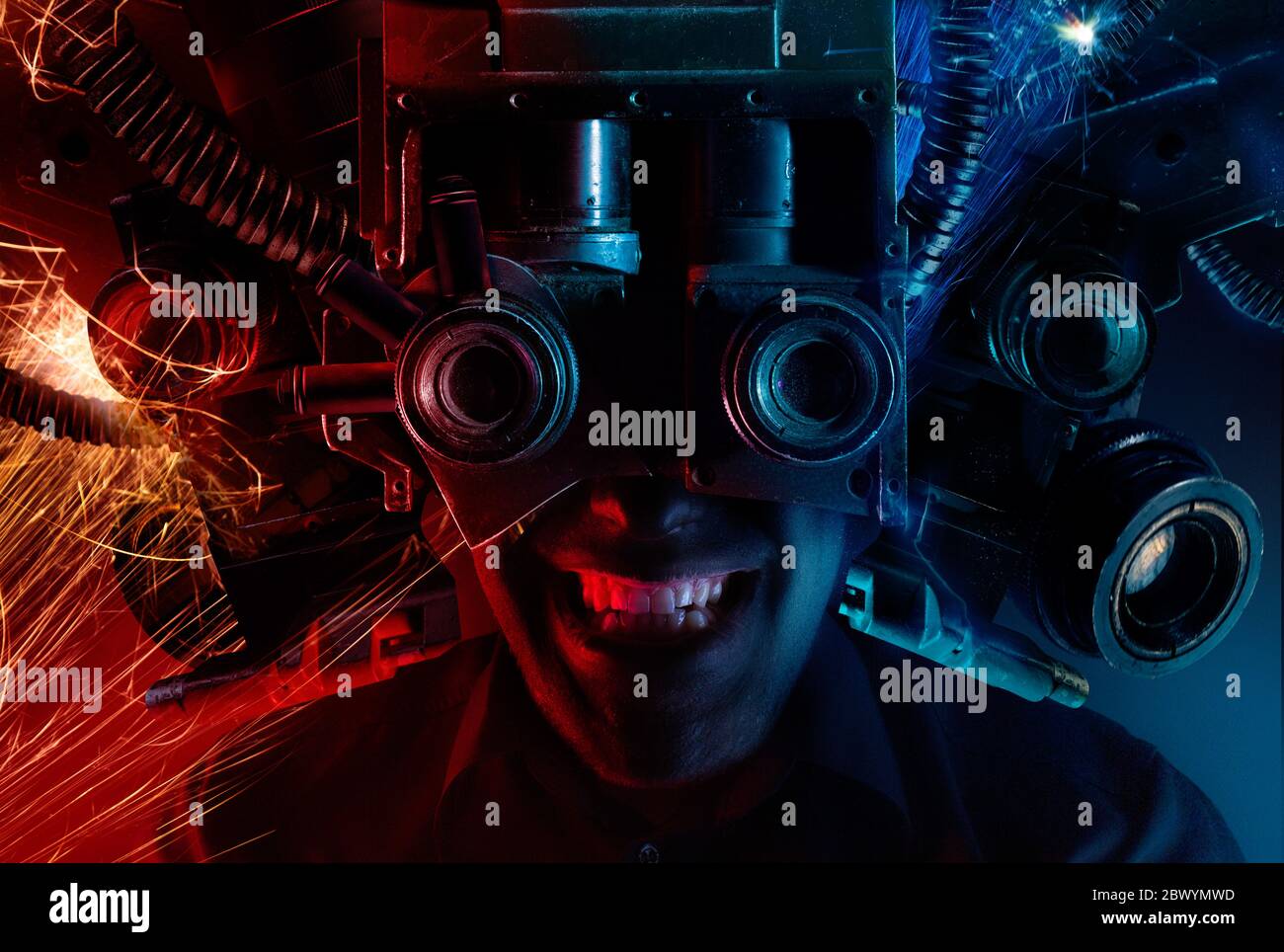 Photo of a cyberpunk male head portrait with robotic helmet with wires, metal parts and binoculars on black background. Stock Photo