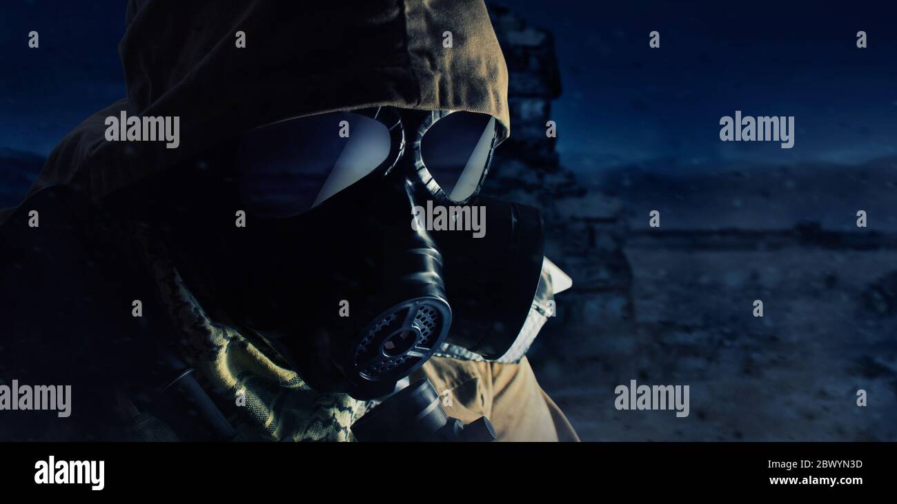 Photo of a desert post-apocalyptic soldier in tactical jacket, gas mask and armor face standing on night wasteland background side view. Stock Photo