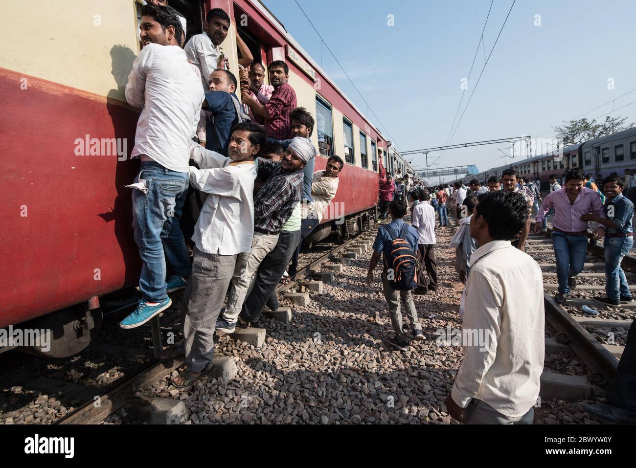 Commuters hang out of an overcrowded Indian Railways train, at Noli Railway Station near