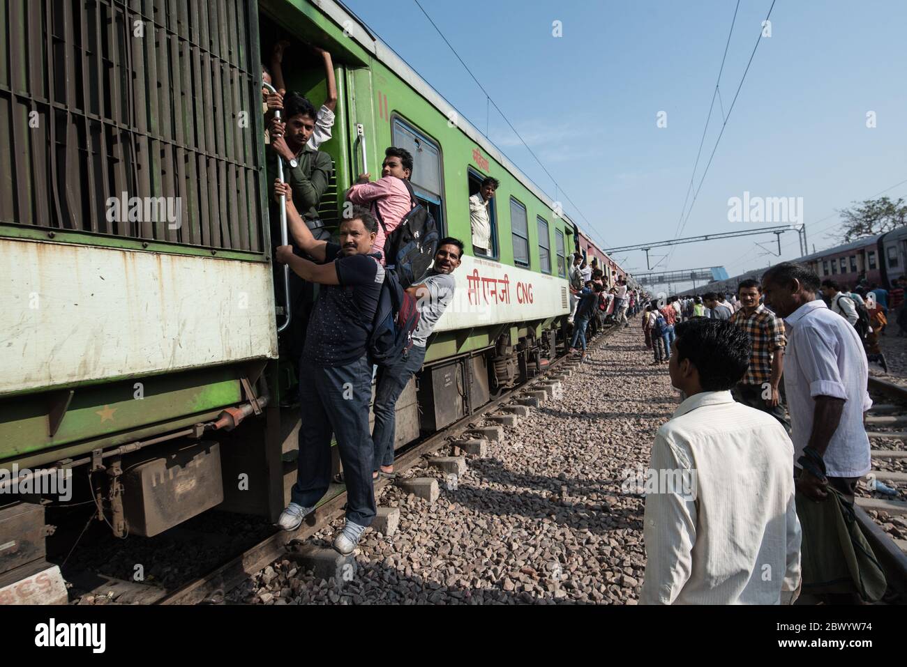 Commuters hang out of an overcrowded Indian Railways train, at Noli Railway Station near