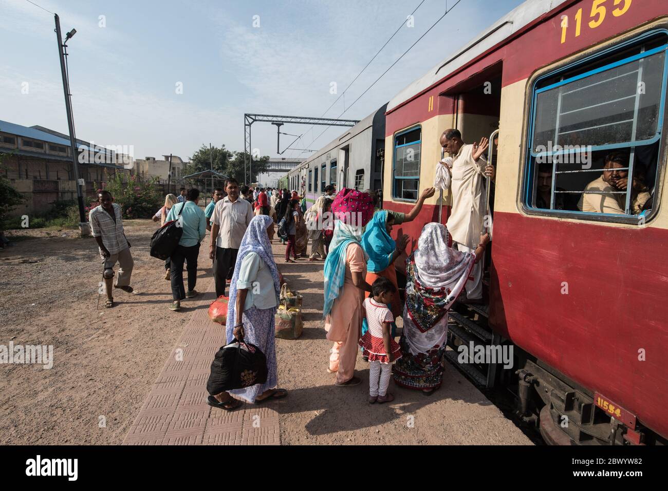 Commuters hang out of an overcrowded Indian Railways train, at Noli Railway Station near