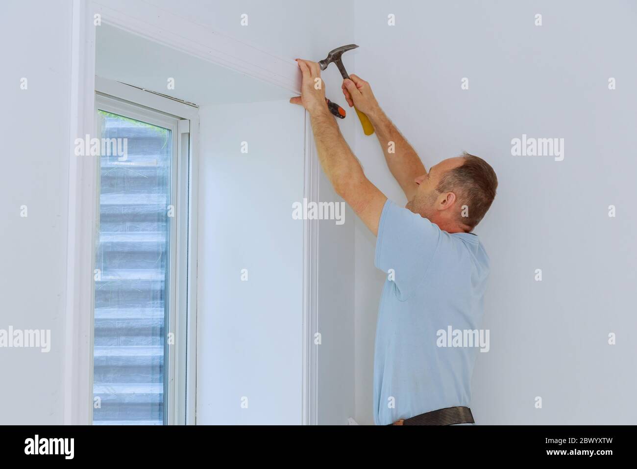 Worker installing trim around a window molding installed moldings