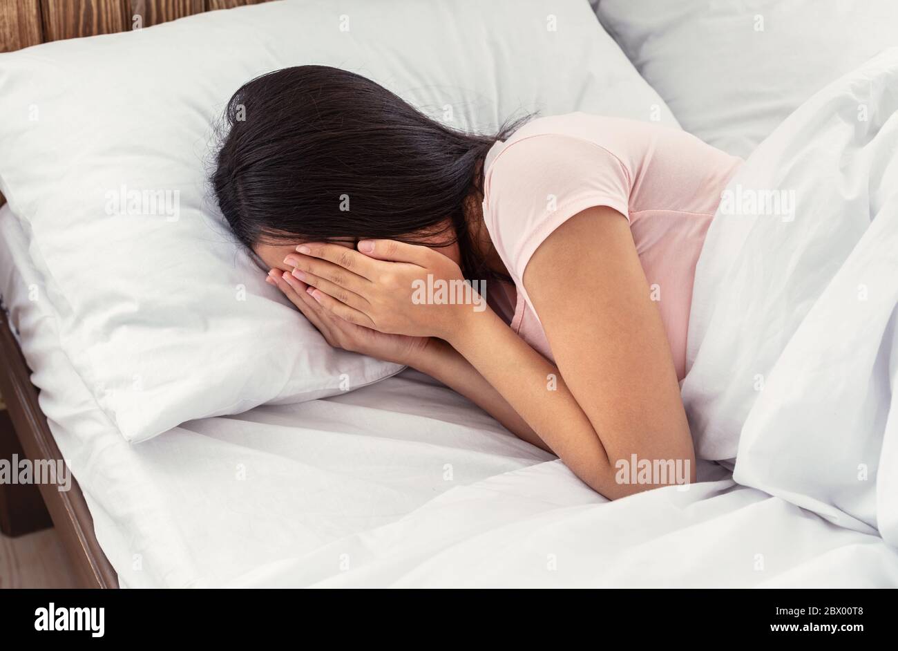 Unrecognizable Girl Crying Covering Face With Hands Lying In Bed Stock Photo