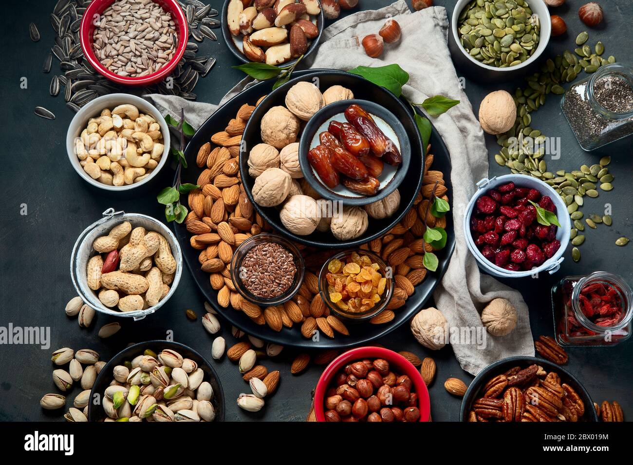 Different types of nuts, seeds and dried fruits on black background