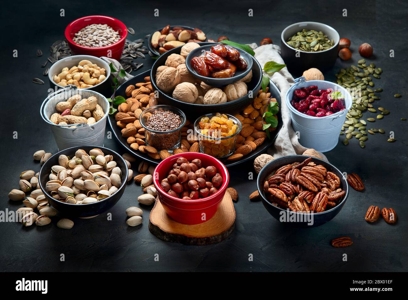Different types of nuts, seeds and dried fruits on black background