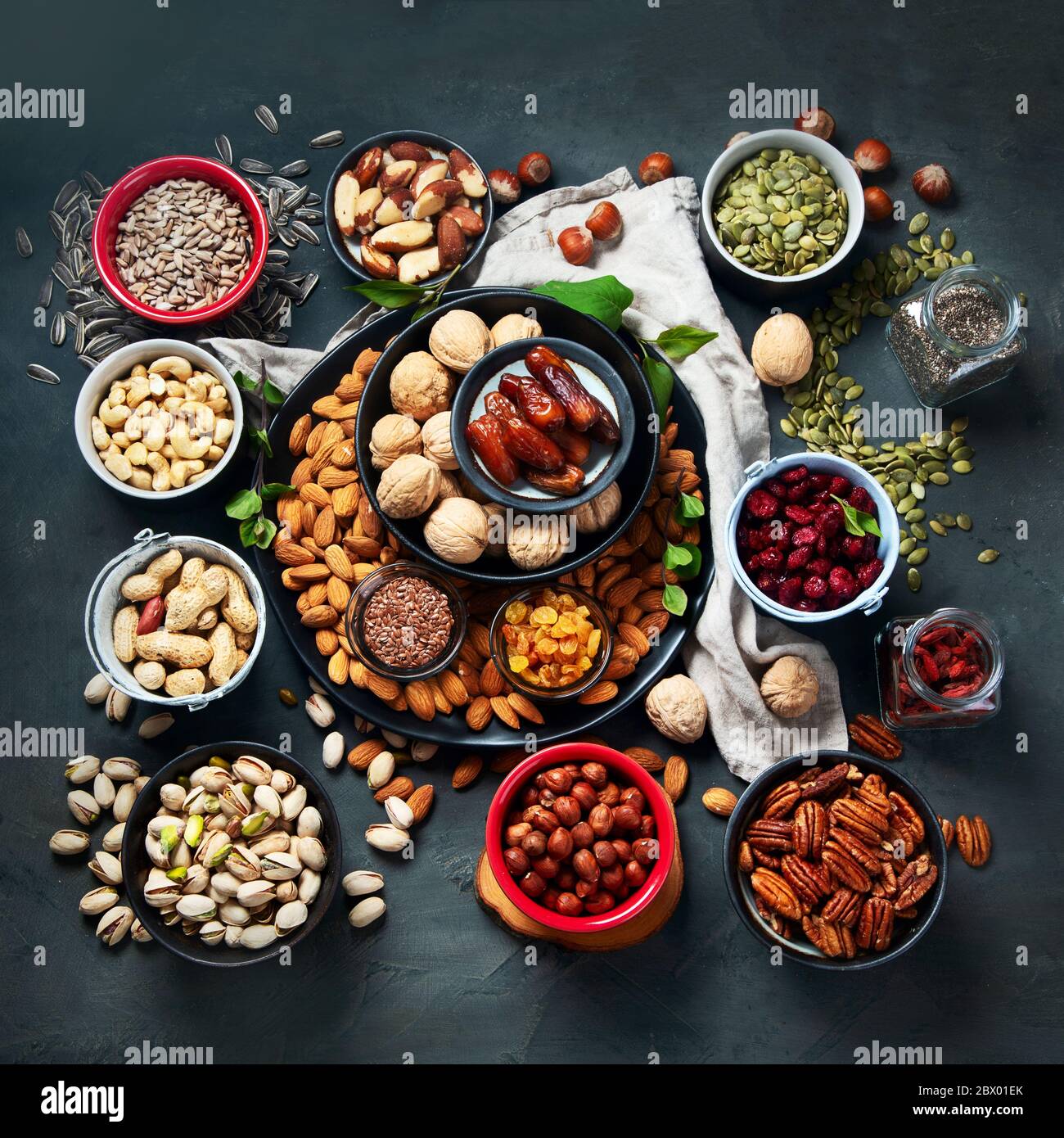 Different types of nuts, seeds and dried fruits on black background