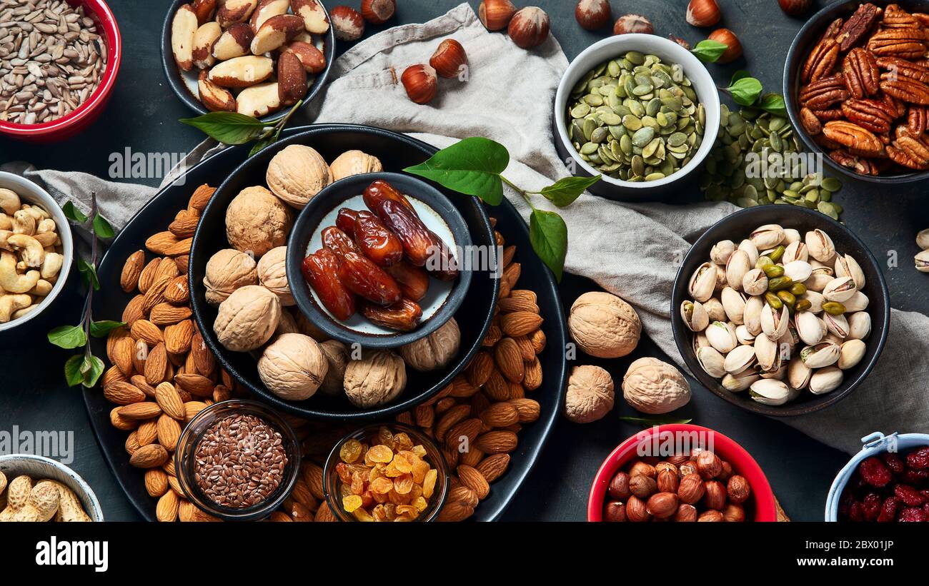 Different types of nuts, seeds and dried fruits on black background