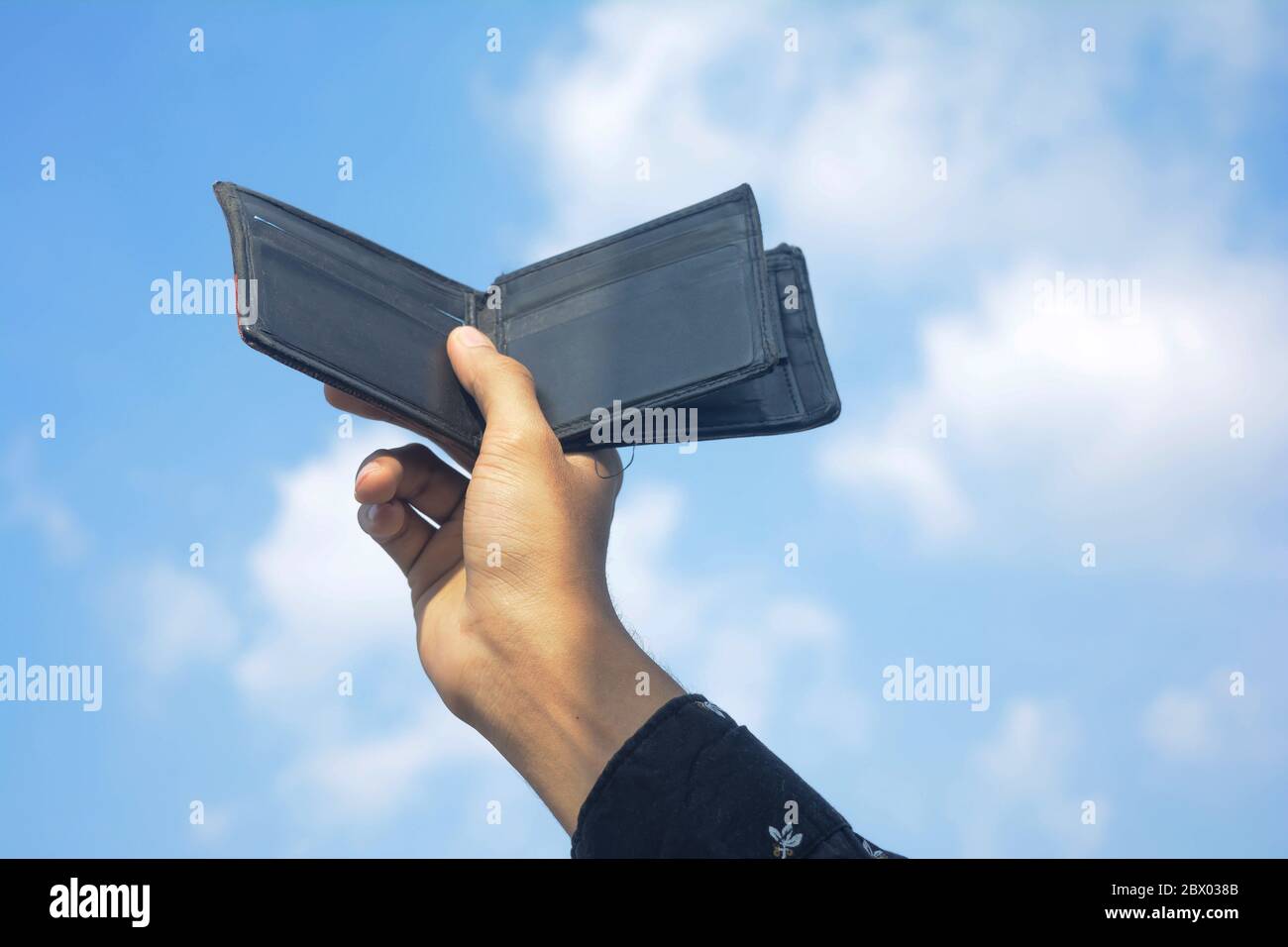 Man hands showing black wallet on sky and cloud background. Stock Photo