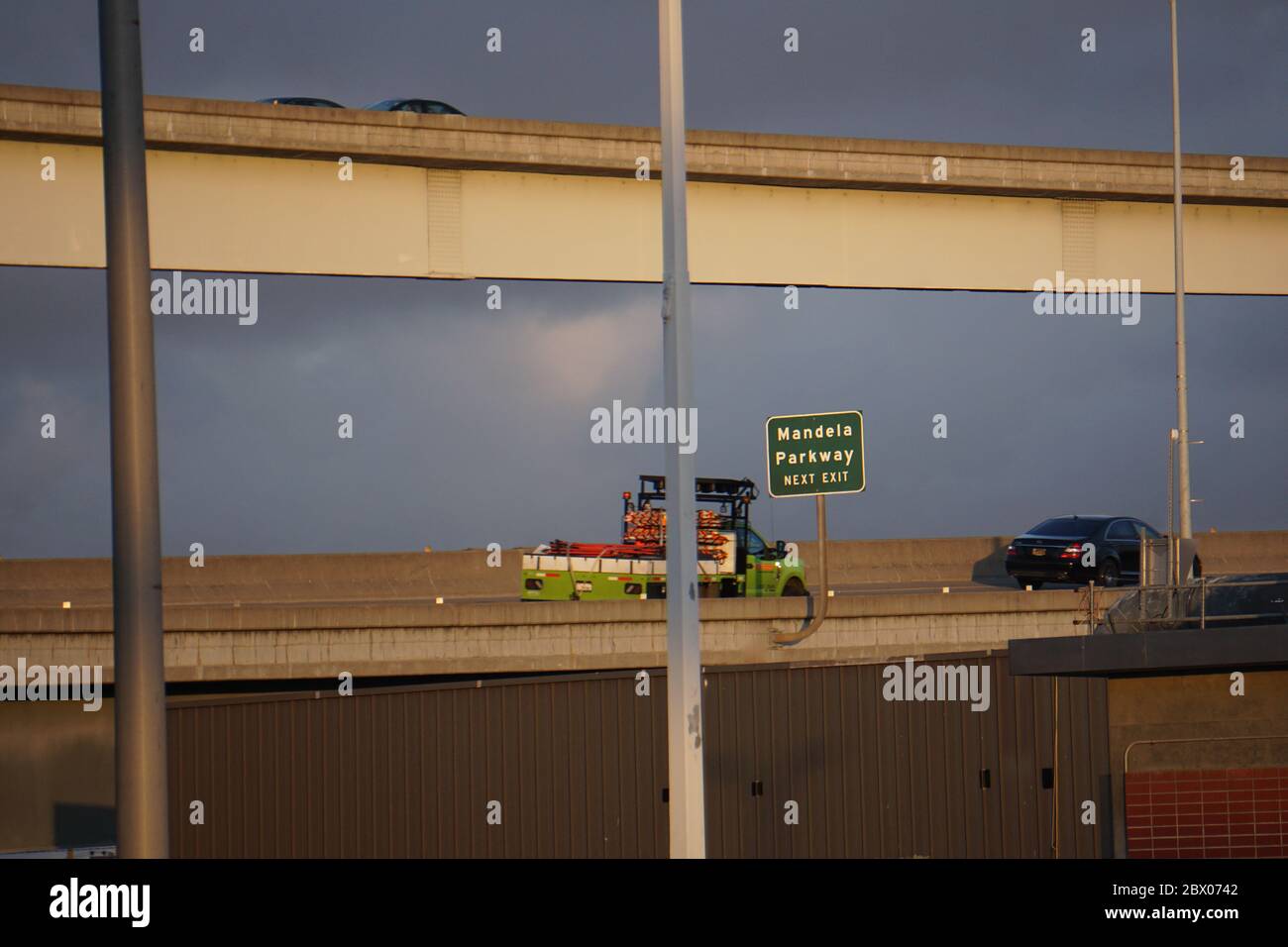 Truck and cars on highway overpass with green Next Exit sign for Mandela Parkway. Road transportation system. West Oakland, California, USA Stock Photo