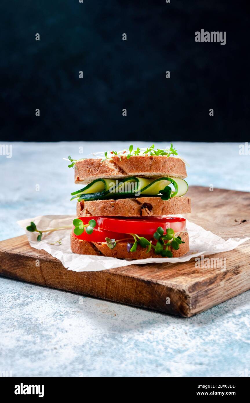 Homemade Healthy Sandwich with Wholegrain Bread, Cucumber, Tomato and Micro Herbs Watercress Salad on Wooden Board. Stock Photo