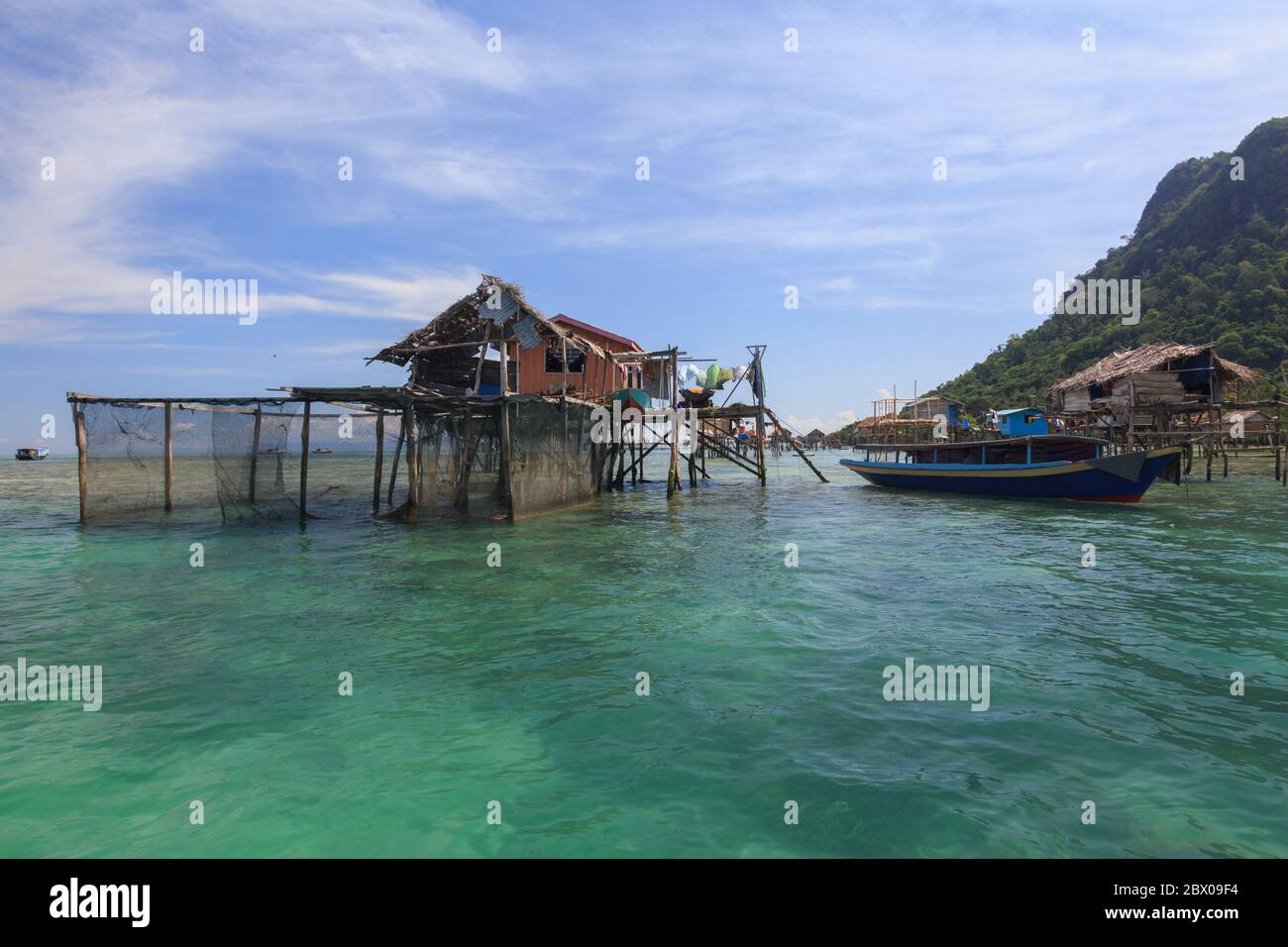 Amazing landscape view of old sea gypsy house in Semporna, Sabah with blue sky background and crystal clear water sea - Travel Concept Stock Photo