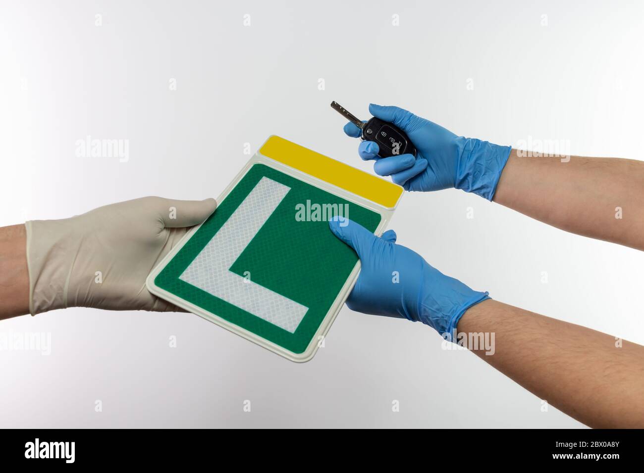 Spanish driver school teacher giving learner green driver sign, a student holding car key, using protective gloves for covid-19 pandemic prevention Stock Photo