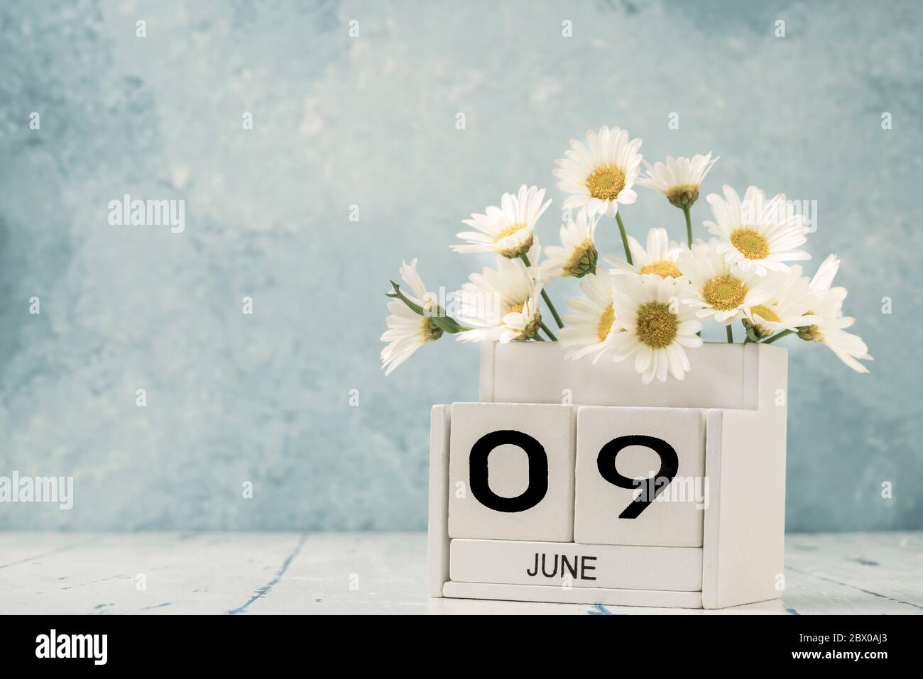 White cube calendar for june decorated with daisy flowers over blue ...