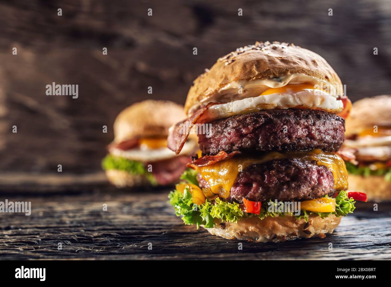 Delicious double beef burger with melted cheese in a vintage surroundings with two more burgers in the background Stock Photo