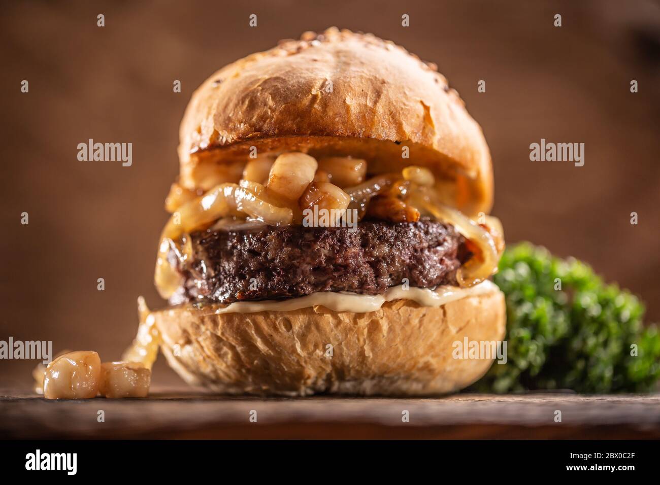 Beef burger with melted cheese, caramelized onions in a sesame bun Stock Photo