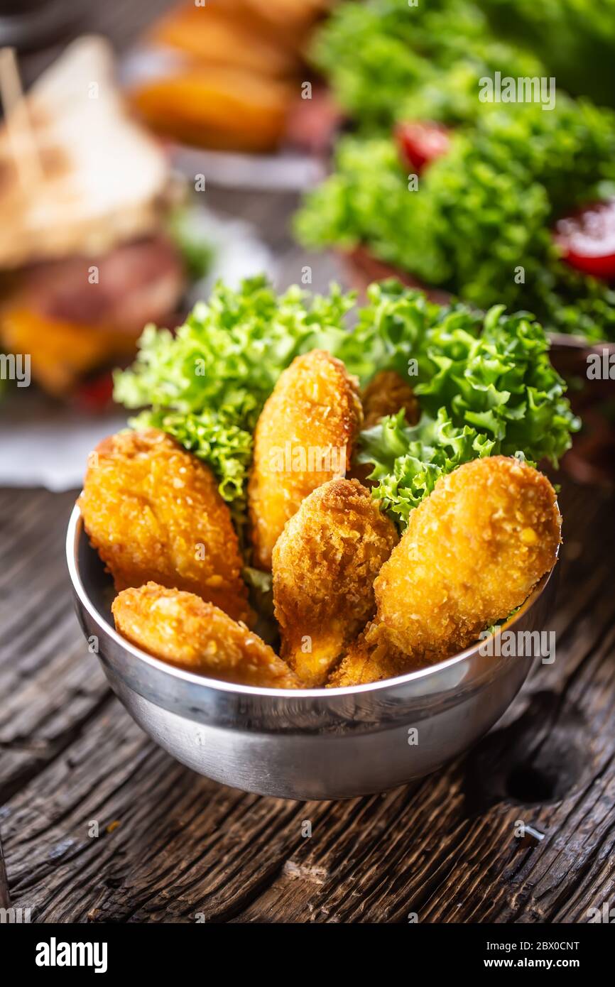 Chicken nuggets with salad in a metal bowl on a rustic wooden surface Stock Photo