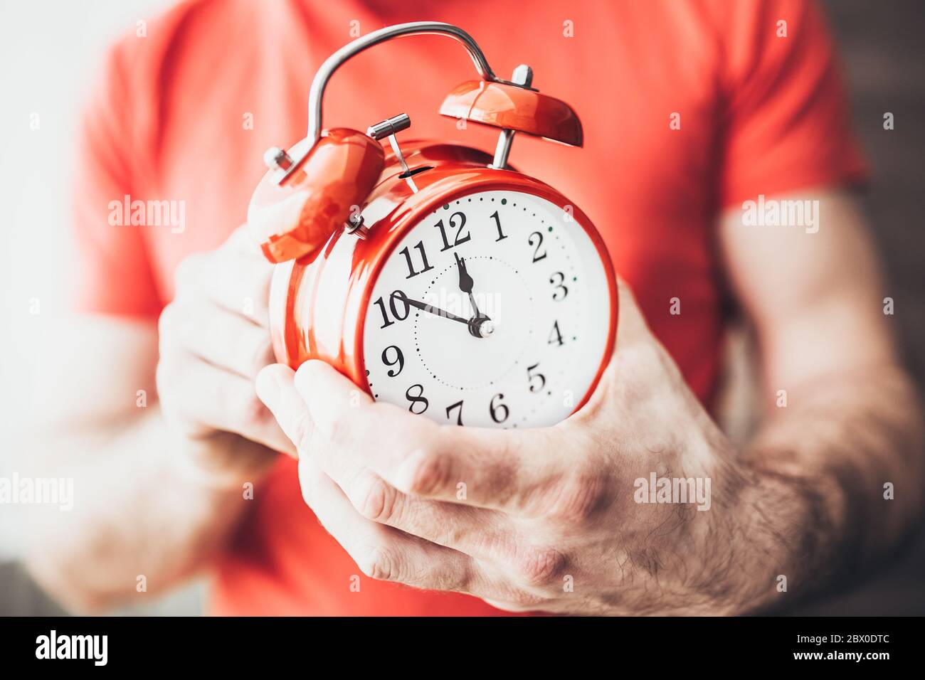 Red alarm clock in the hands - setting the timer for 10 minutes before the new year Stock Photo
