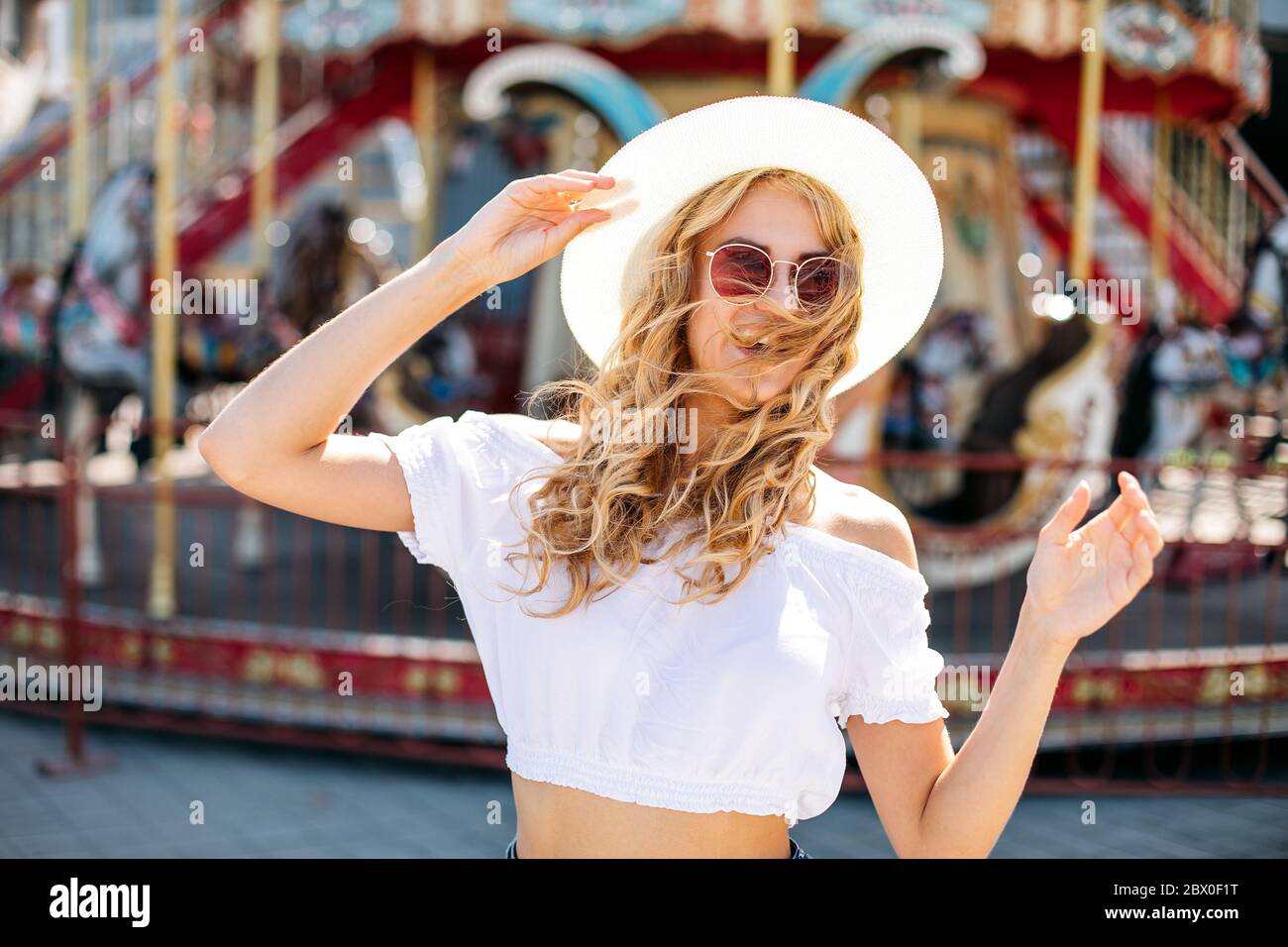 happy smiling pretty girl having fun.stylishly dressed in short denim shorts and t-shirts, sunglasses.posing on the background of a ferris wheel. Stock Photo