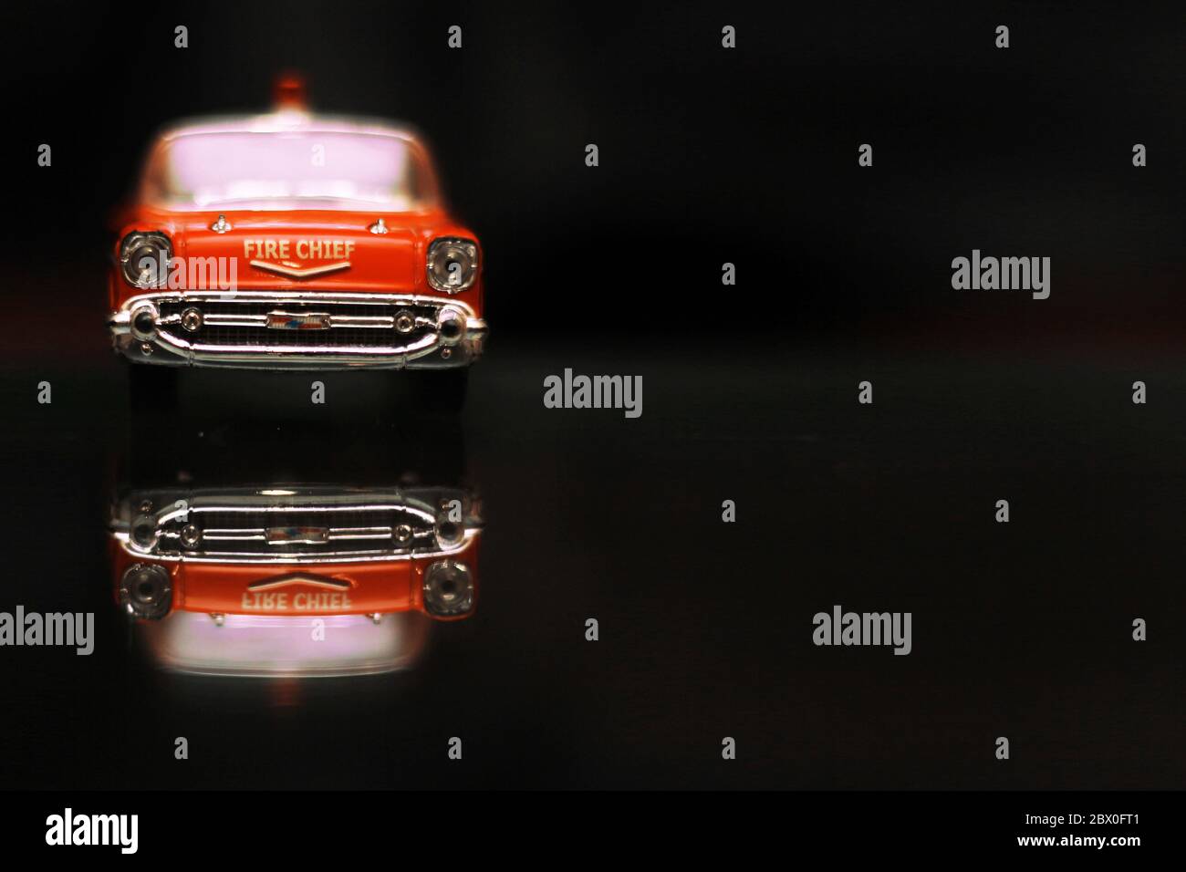 Beautiful red toy vintage car of fire chief on black background and