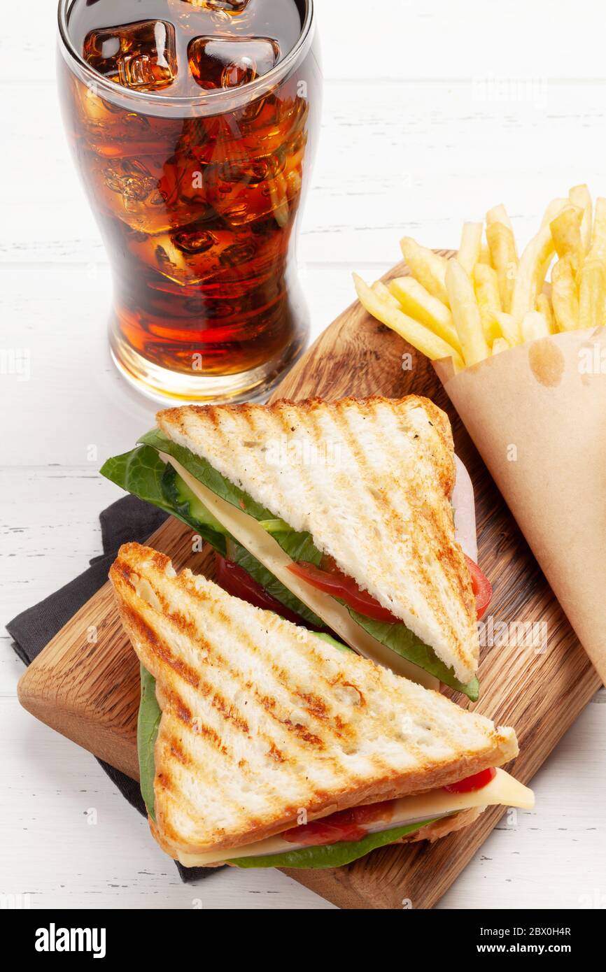 Club sandwich, potato fries chips and glass of cola drink with ice