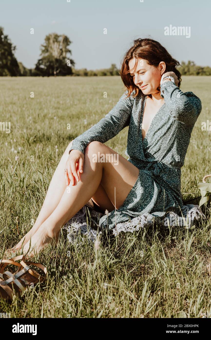Outdoor fashion portrait of beauty young woman in a light blue dress  sitting on green grass . Summer clothing and accessories Stock Photo - Alamy