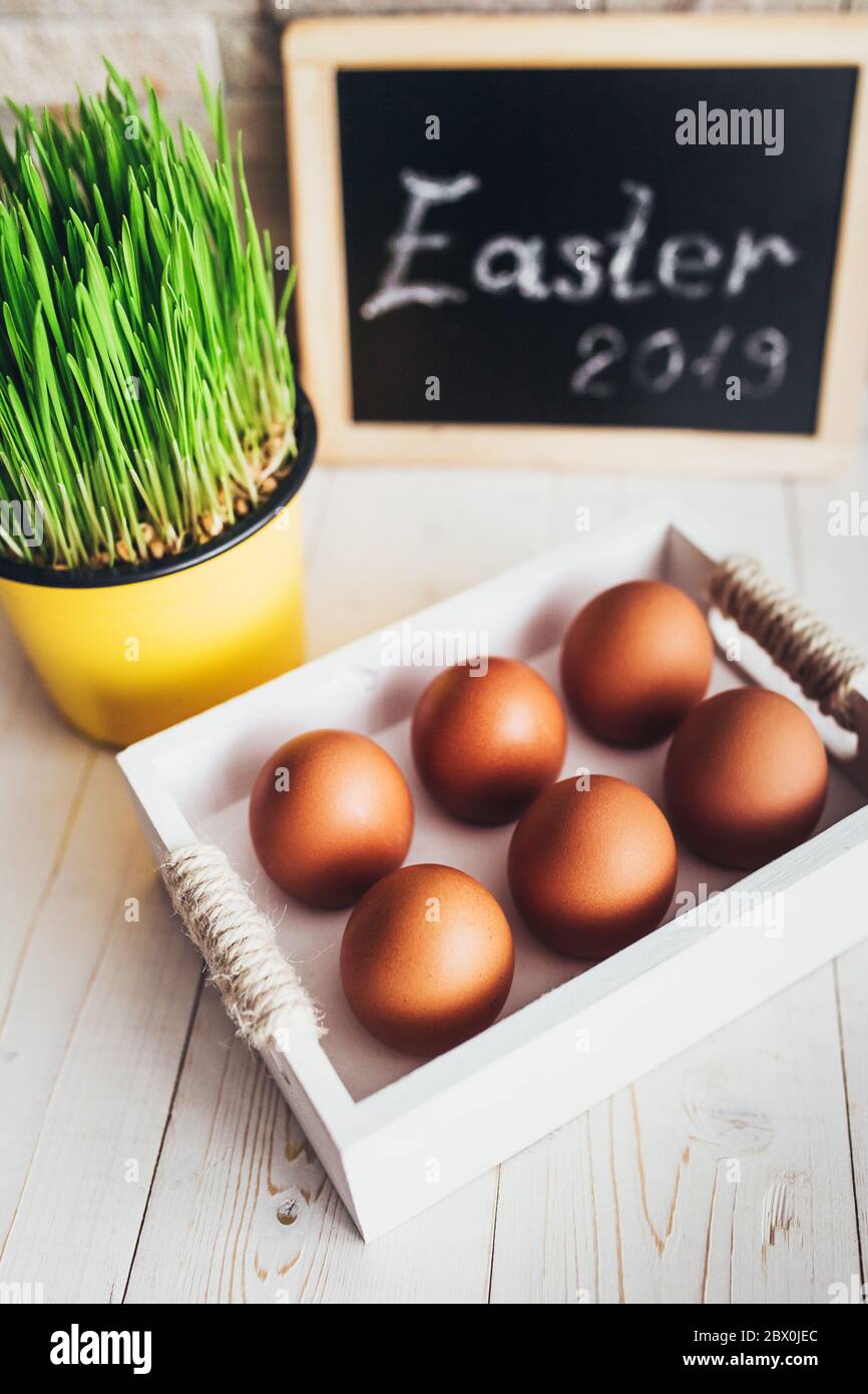 Wooden box with orange chicken eggs on a white rustic table - easter composition Stock Photo
