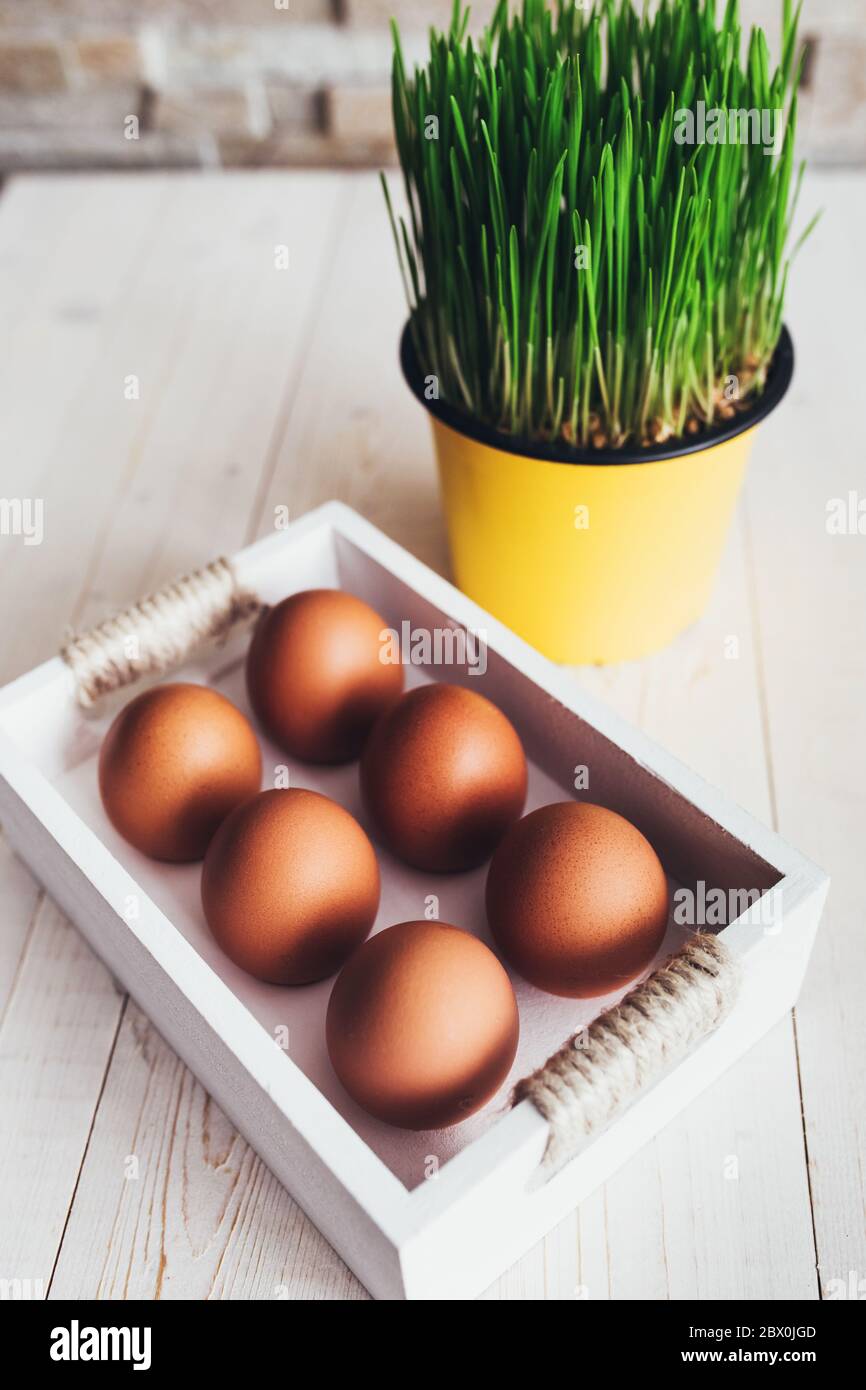 Wooden box with orange chicken eggs on a white rustic table - easter composition Stock Photo