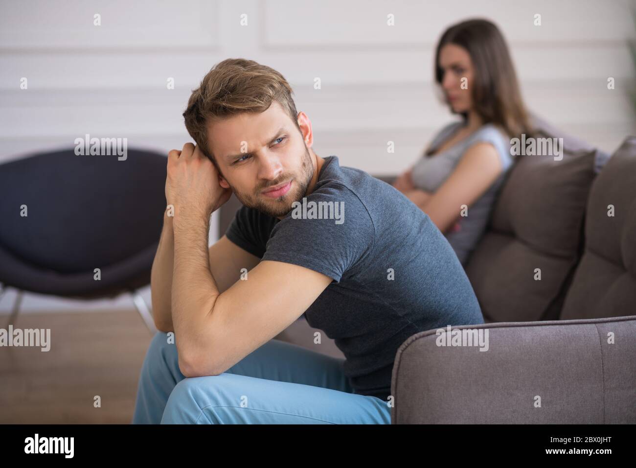 Young couple sitting on the sofa after a quarrel Stock Photo - Alamy