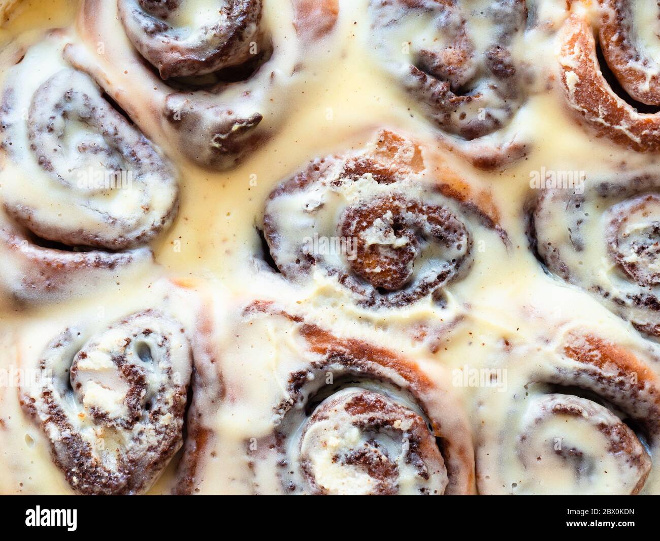 freshly baked cinnamon rolls drenched with sweet cream sauce close up Stock Photo