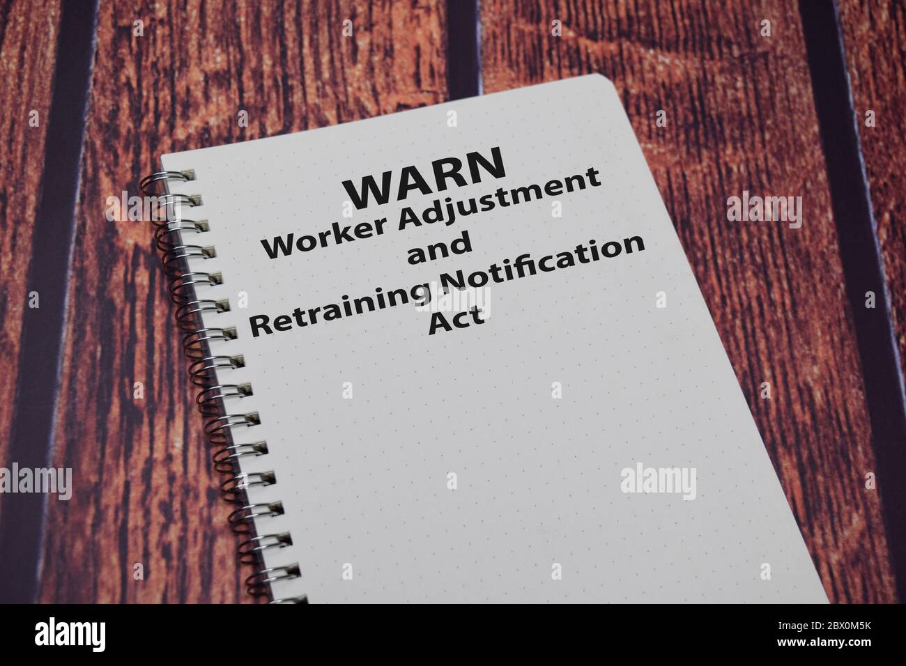 Book about WARN - Worker Adjustment & Retraining Notification Act isolated on wooden table. Stock Photo