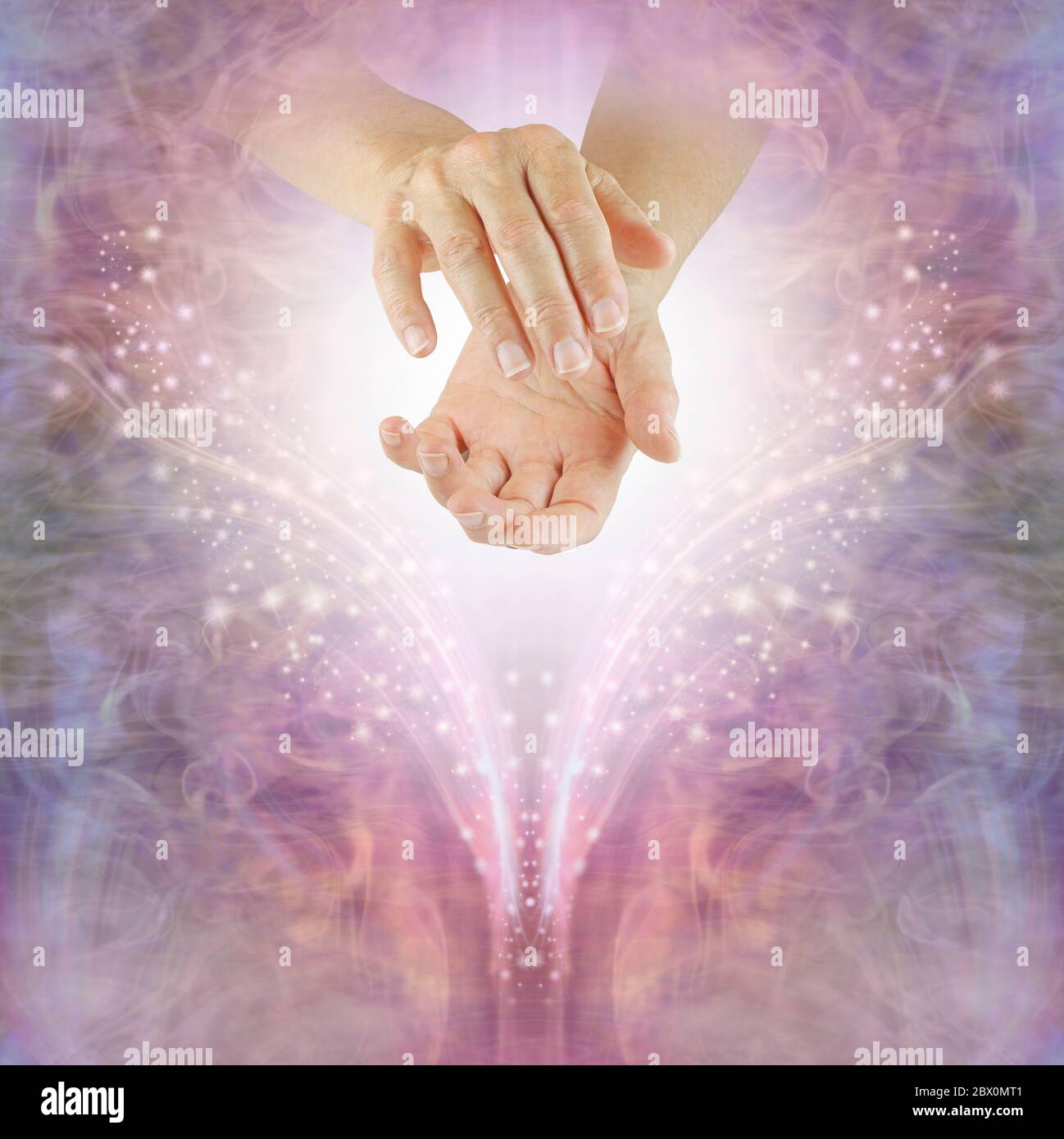 Sending out Reiki healing energy across the ether - female with cupped hands against a beautiful pink sparkling angelic background with copy space Stock Photo