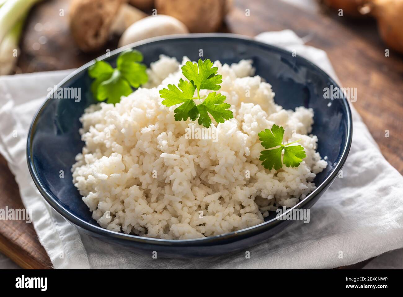 Bowl of steamed rice with mushrooms and leaks in the background Stock Photo