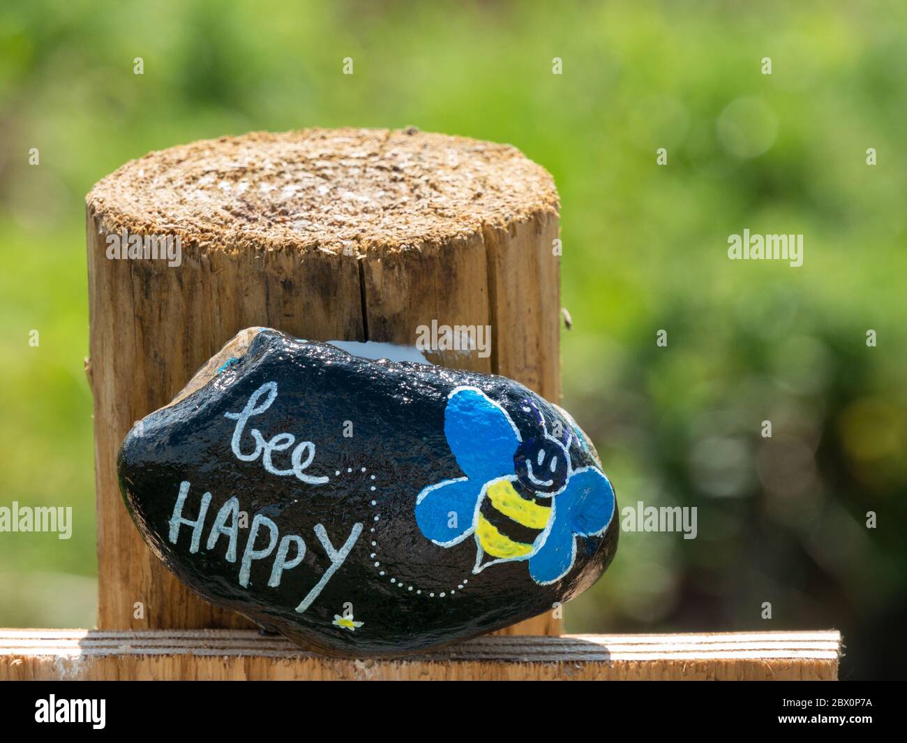 'Bee Happy' painted stone on gatepost in Leicestershire during Covid-19 lock-down, England, UK Stock Photo