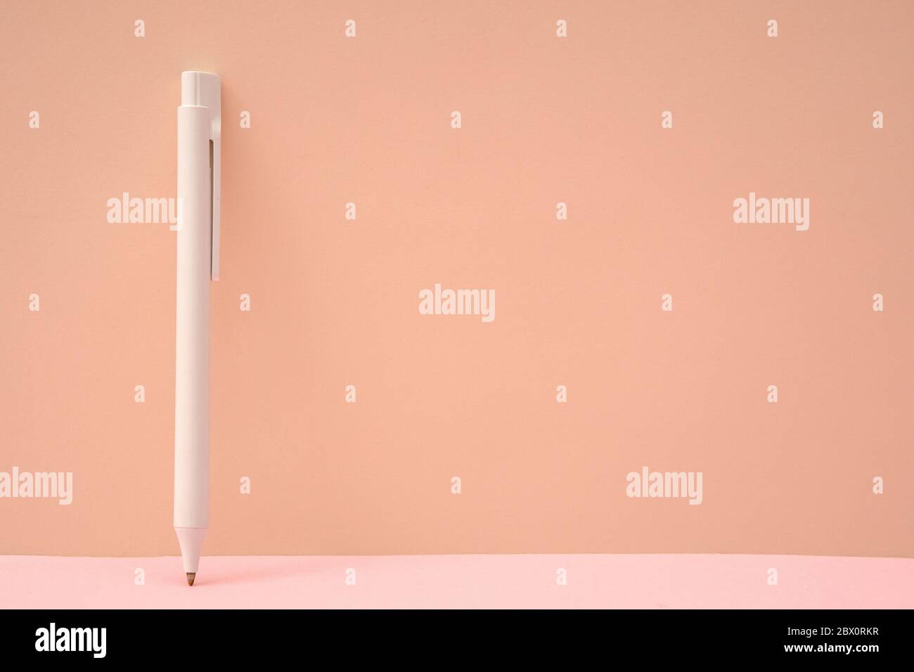 Pink color background and white ballpoint pen Stock Photo