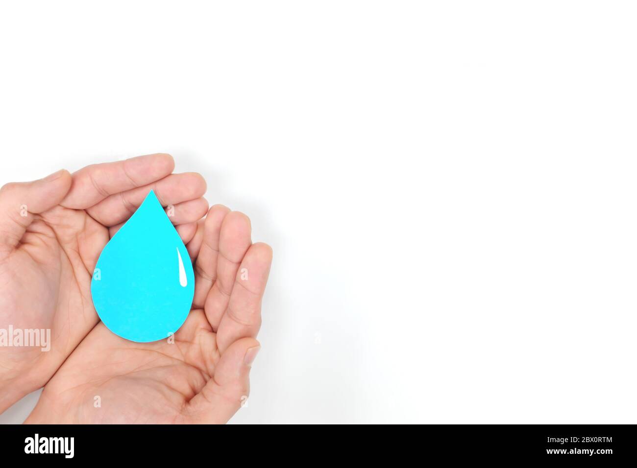 Male hands holding a blue water drop in blue background. Wash hands, csr, save water and world oceans day concept. Top view with copy space. Stock Photo
