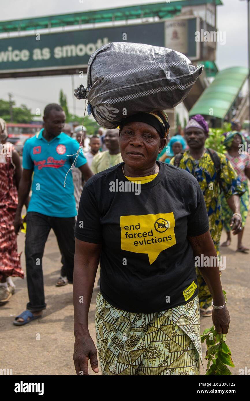 Lagos, Nigeria. A woman (one of the displaced residents of Otodo Gbame) carries her belongings on her head in a peaceful protest in the street of  Lagos.    More than 6 months after the court ruling, the state was yet to fulfill its promises and obey the court orders. Otodo Gbame and other waterfront communities staged a peaceful protest to the government house. The protest was billed to last for three nights and days, however, the Nigeria Police Force cracked down on the protesters by 12.28am on November 16 and arrested 158 protesters. They were later made to sign an undertaking never to prot Stock Photo