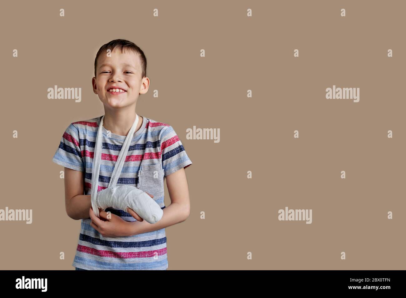 a child in a striped t-shirt with a bandage wrapped around his arm. Arm injury. Stock Photo