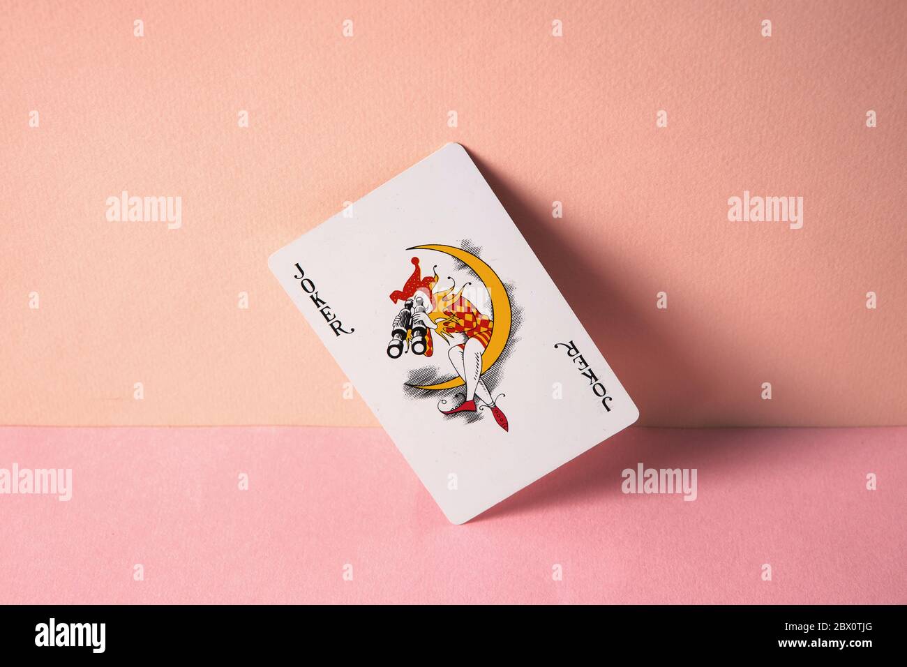 Joker playing card on pink background. Stock Photo