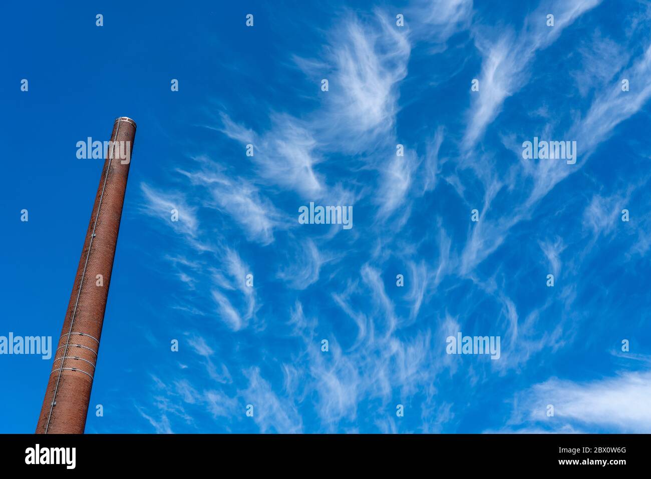 Blue sky with cirrus clouds, filigree ice clouds at high altitude, harbingers of warmer weather, chimneys, emissions Stock Photo