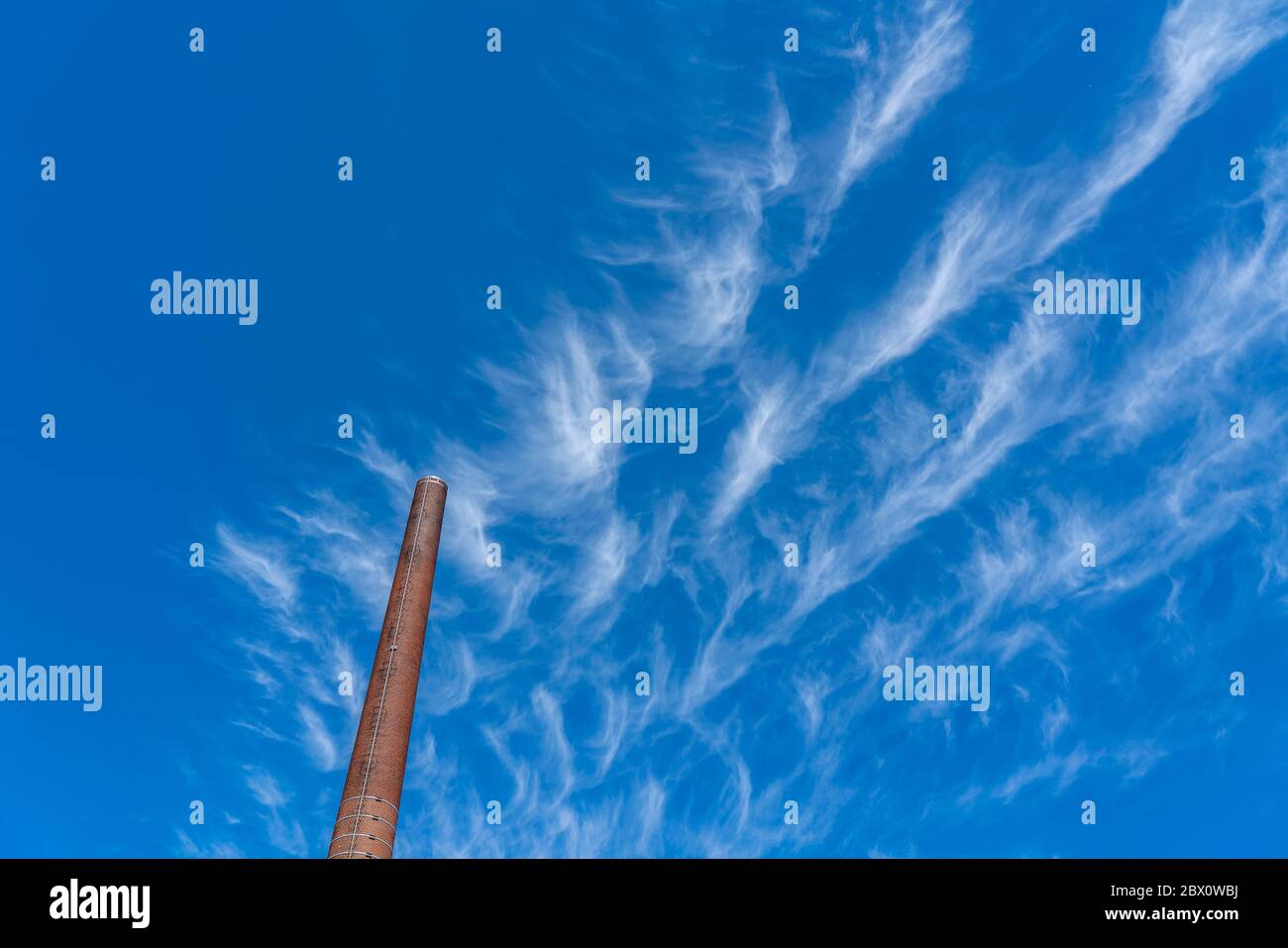 Blue sky with cirrus clouds, filigree ice clouds at high altitude, harbingers of warmer weather, chimneys, emissions Stock Photo