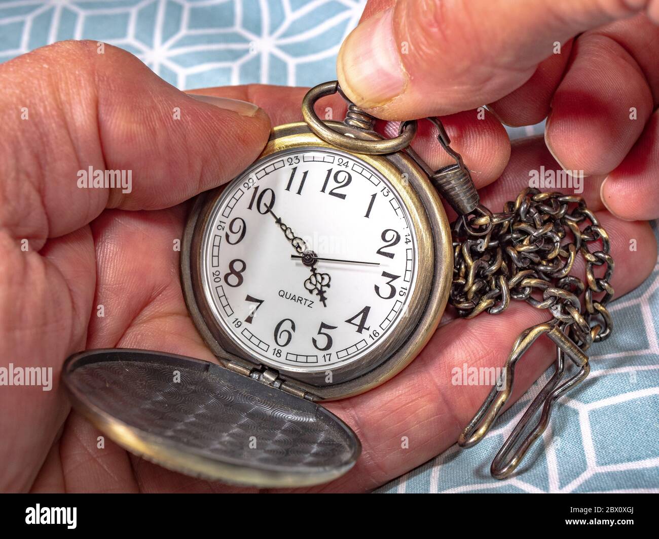 Close POV shot of a man’s hands setting the time on a quartz brass pocket watch with attached chain. Stock Photo