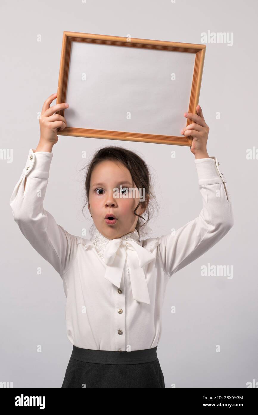 first grade school girl holds a white sheet for the inscription Stock Photo