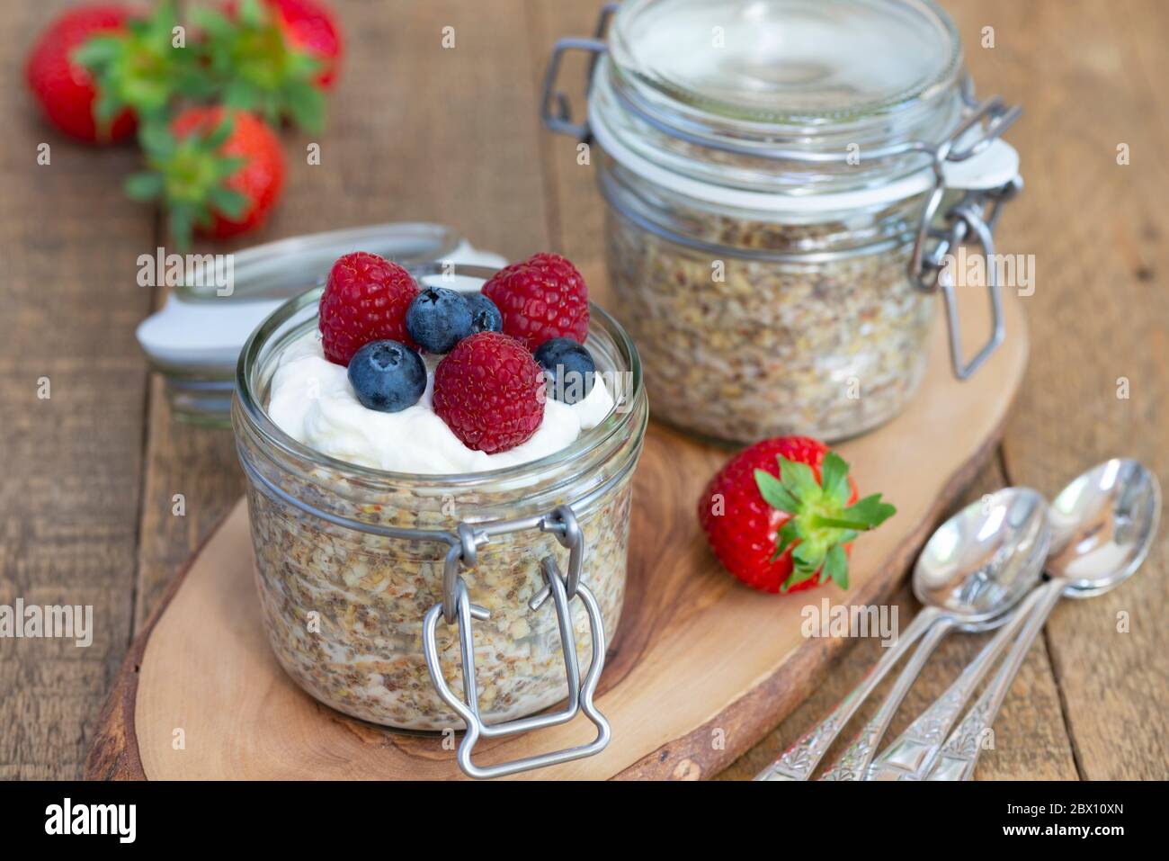 Overnight oats breakfast pots served with Greek yoghurt, blueberries and raspberries. Stock Photo