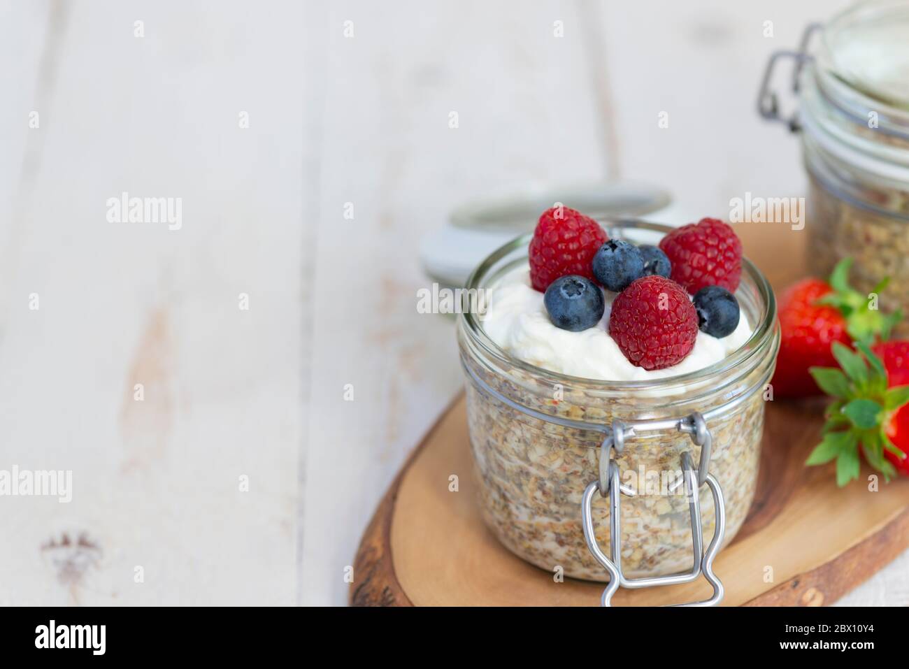 Overnight oats breakfast pots served with Greek yoghurt, blueberries and raspberries. Stock Photo