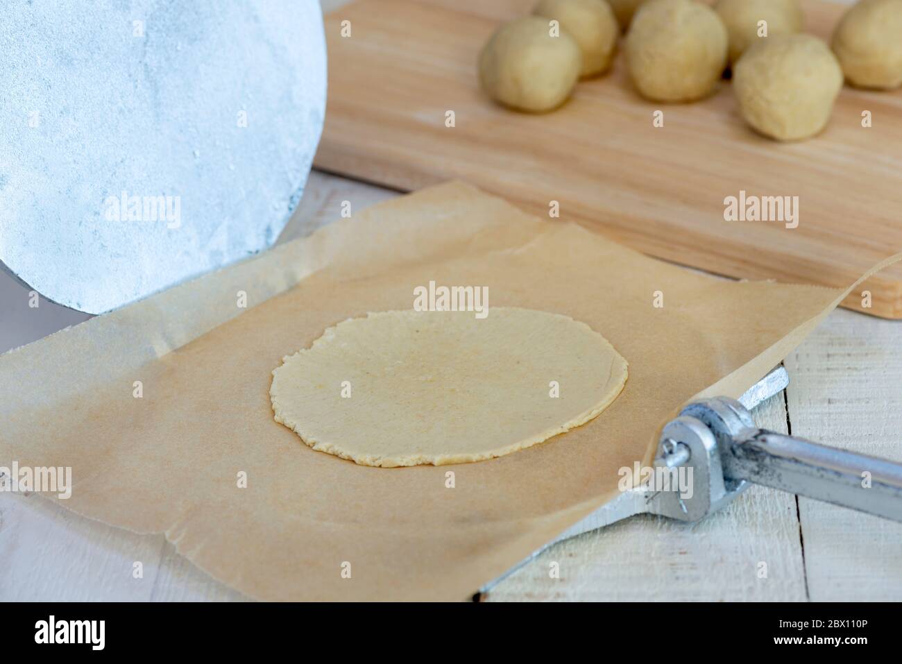 Making authentic corn tortillas - dough ball pressed flat by tortilla press. Stock Photo