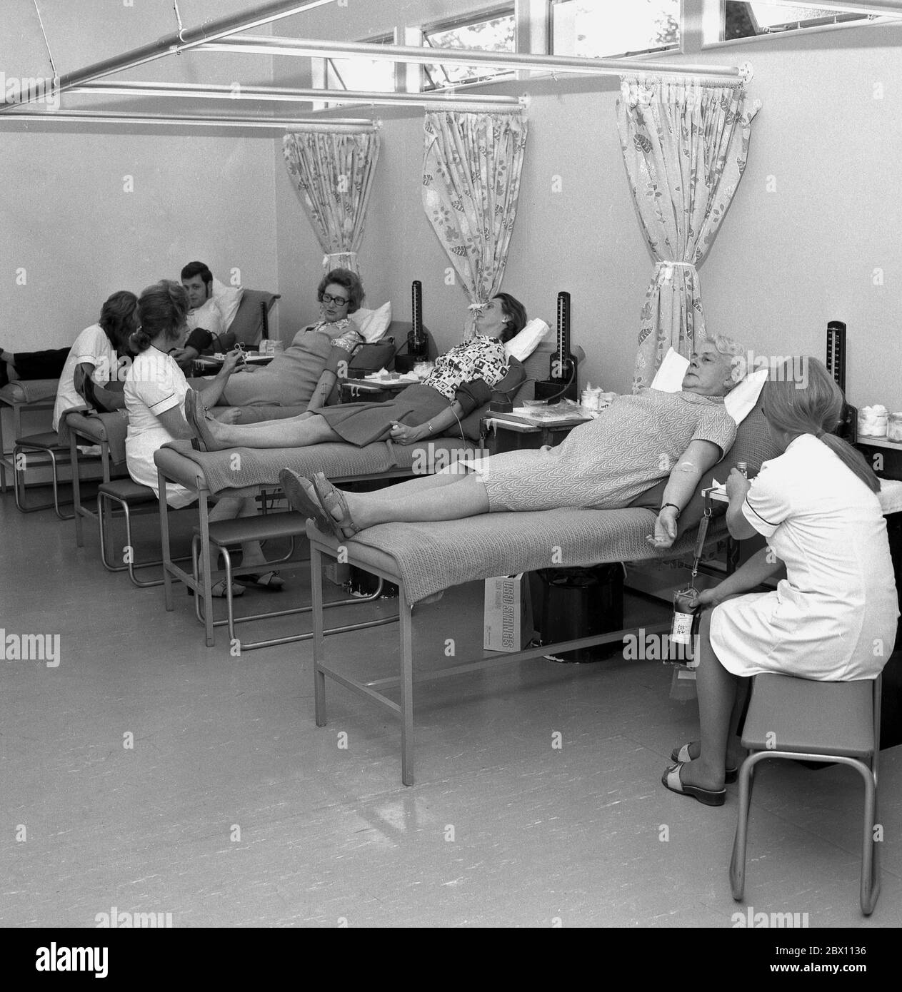 'Blood donors', members of the public lying on surgical beds in a medical or health centre voluntarily giving blood, Lewisham, South London, late 60s, early 1970s. Giving blood for community supply is public-spirited act by people as blood can save lives. Stock Photo