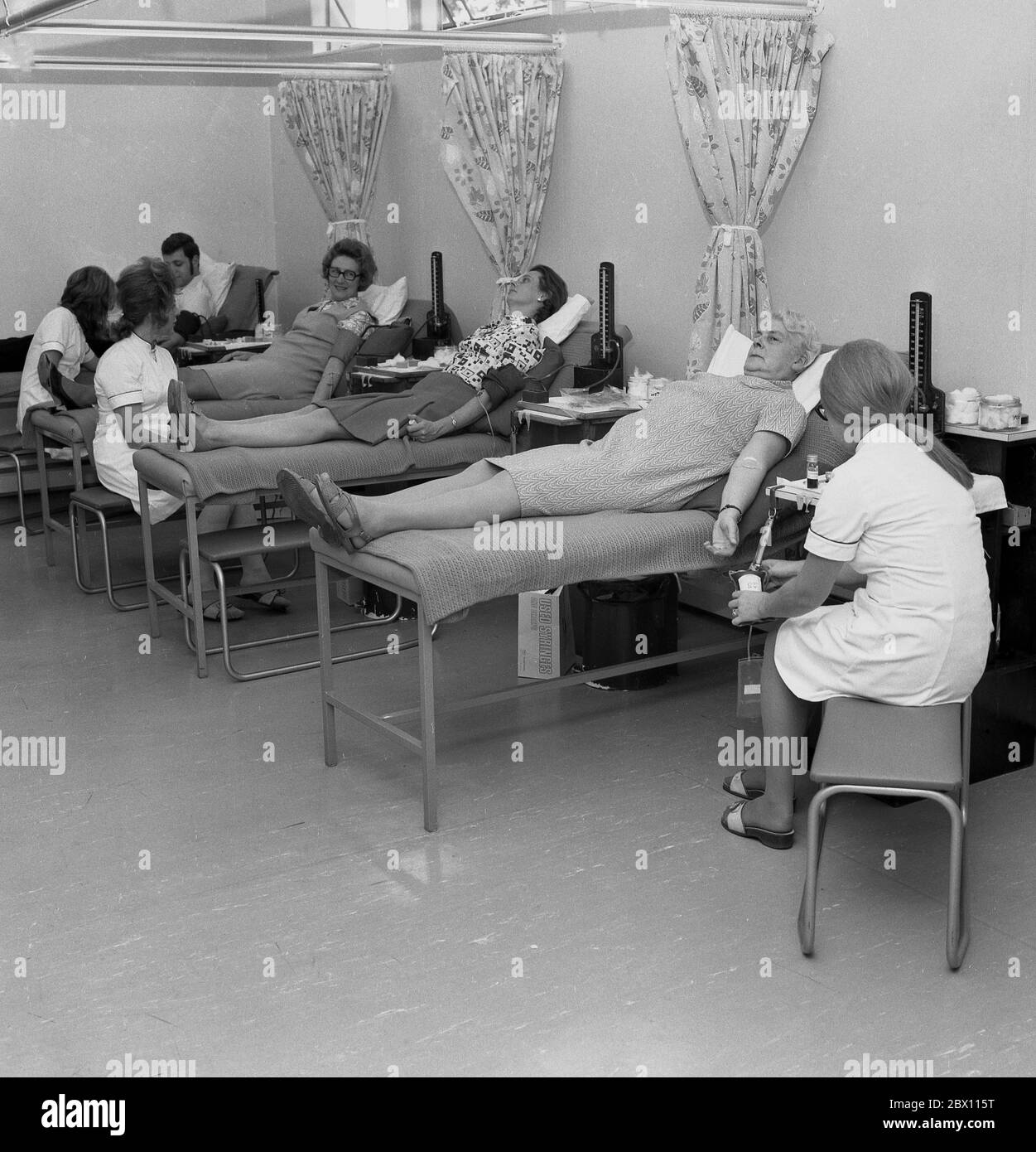 'Blood donors', members of the public lying on surgical beds in a medical or health centre voluntarily giving blood, Lewisham, South London, late 60s, early 1970s. Giving blood for community supply is public-spirited act by people as blood can save lives. Stock Photo