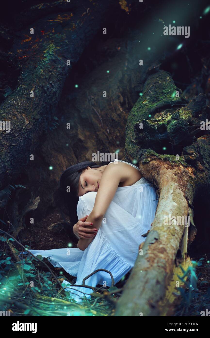 Beautiful dark woman sleeping among forest spirits and fairies . Fantasy and magic Stock Photo