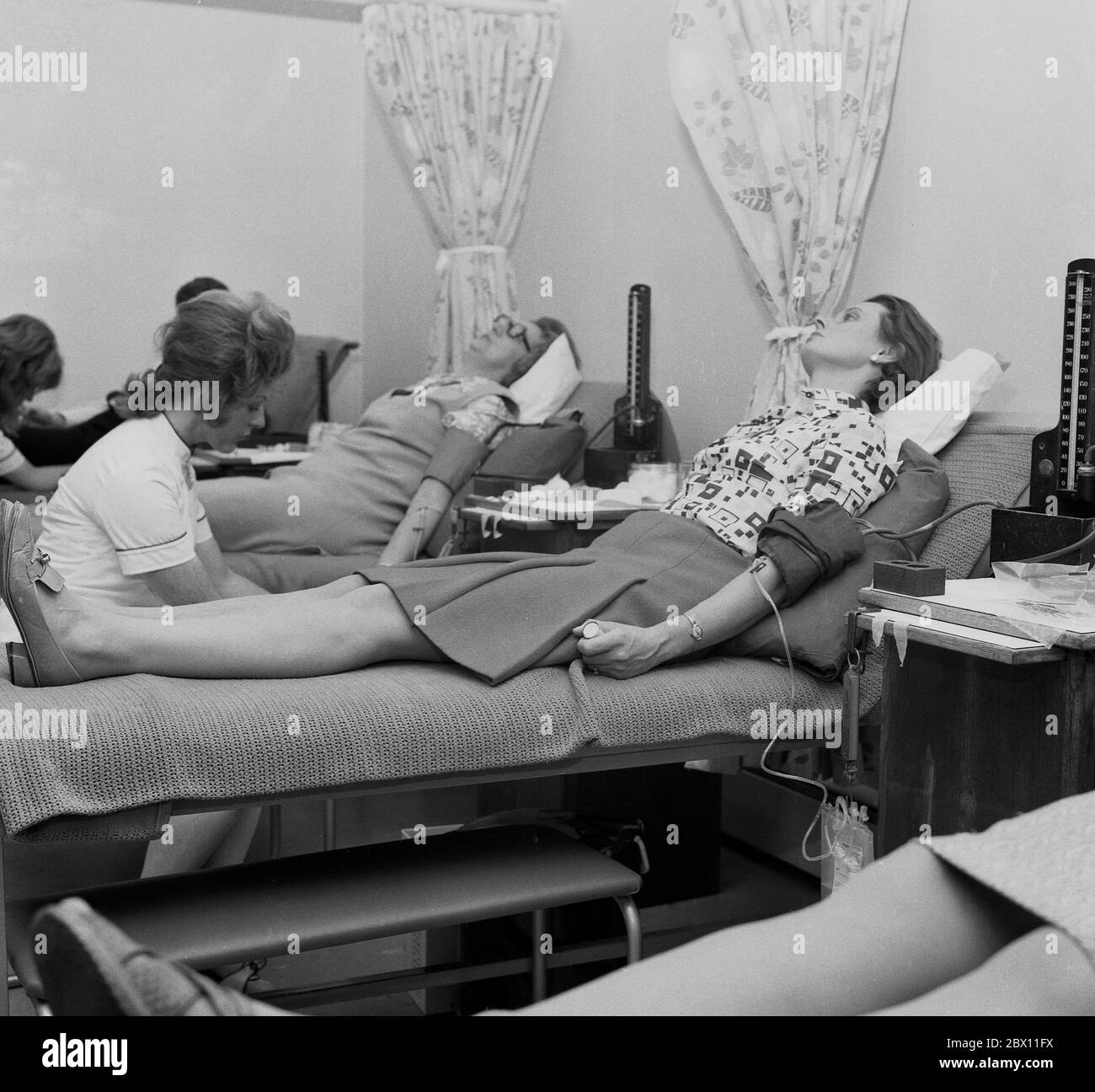'Blood donation', attended by a female nurse, a lady lying on a blanket on a surgical bed in a medical or health centre giving blood from her arm, Lewisham, South London, late 60s, early 1970s. Stock Photo